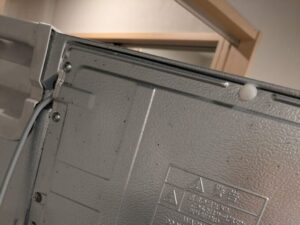 神奈川県横浜市港北区の住宅にて、チャバネゴキブリの主要な潜伏箇所となる冷蔵庫背面の熱源部を精密調査。モーター熱で温暖な環境に巣が作られていないか確認する様子