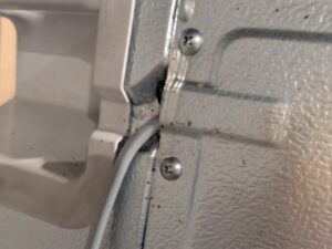 先ほどの冷蔵庫背面をクローズアップ。熱源パーツの隙間やパネルに密集した黒い粒が、集合フェロモンを放つチャバネゴキブリ特有の糞であることを特定した証拠写真