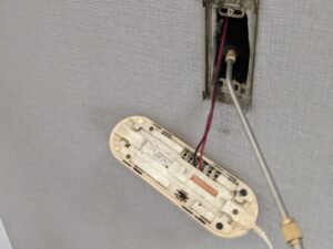 中野区のアパートで入居前の壁面インターホンを外して内部を調査するゴキブリ駆除業者